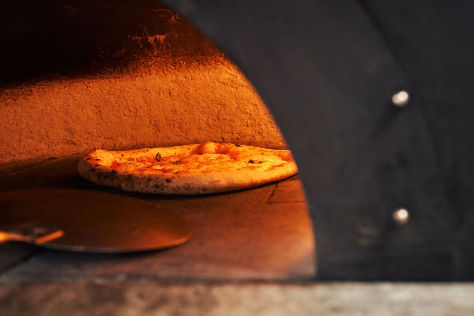 Pizza mit Olivenöl im glühend heißen Holzofen